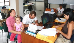 Franciele e Nelson Szupka, com a filha Letícia, assinam a documentação que será enviada à Caixa e Cooperhaf para análise: família está no primeiro grupo contemplado pelo programa