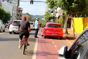 Enquanto agente do Debetran orienta veículo parado sobre a ciclofaixa, ciclista é obrigado a desviar e dividir espaço com os carros na rua